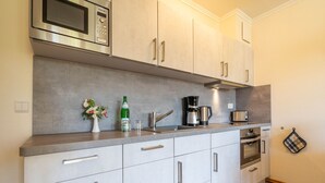 A modern kitchen with stainless steel appliances, a coffee maker, and a kettle on the countertop. - Comfort apartment with 1 bedroom and terrace on the first floor (Ostseebad Binz)