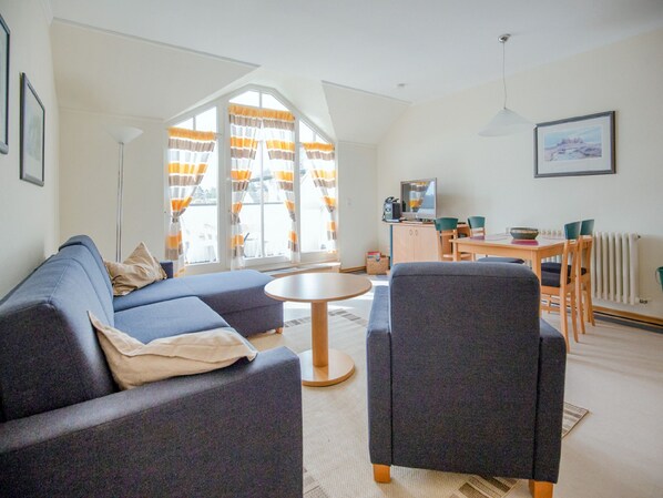 Un salon moderne comprenant un canapé, des fauteuils, une table basse et un coin repas avec une table et des chaises.
