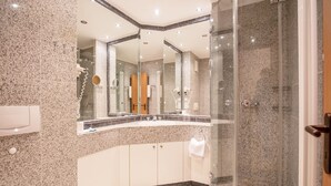 Een moderne badkamer met een granieten aanrechtblad, een douche met glazen wanden en een grote spiegel.