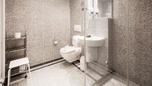 A bathroom with a marble wall, a toilet, a sink, and a glass shower enclosure. - Comfort plus apartment with 1 bedroom and balcony on the top floor (Ostseebad Binz)