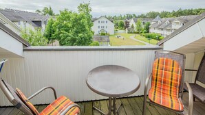 A balcony with two chairs and a small table, overlooking a residential area with houses and trees. - Comfort plus apartment with 1 bedroom and balcony on the top floor (Ostseebad Binz)