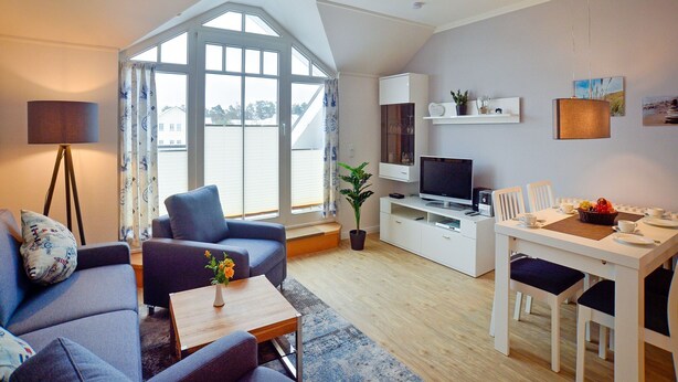 A modern living room with a sofa, coffee table, and dining area. - Comfort plus apartment with 1 bedroom and balcony on the top floor (Ostseebad Binz)