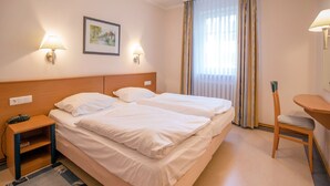 A hotel room with two beds, a desk, a chair, a nightstand, and a painting on the wall. - Comfort apartment with 1 bedroom and terrace on the first floor (Ostseebad Binz)