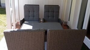 A patio with two grey cushioned chairs and a wicker table. - Comfortplus vacation apartment with 1 bedroom and terrace on the first floor (Ostseebad Binz)