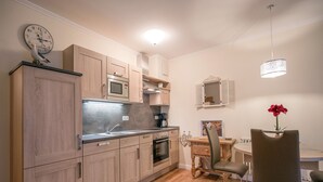 A modern kitchen with wooden cabinets, a built-in microwave, and a dining area with a table and chairs. - Comfortplus vacation apartment with 1 bedroom and terrace on the first floor (Ostseebad Binz)