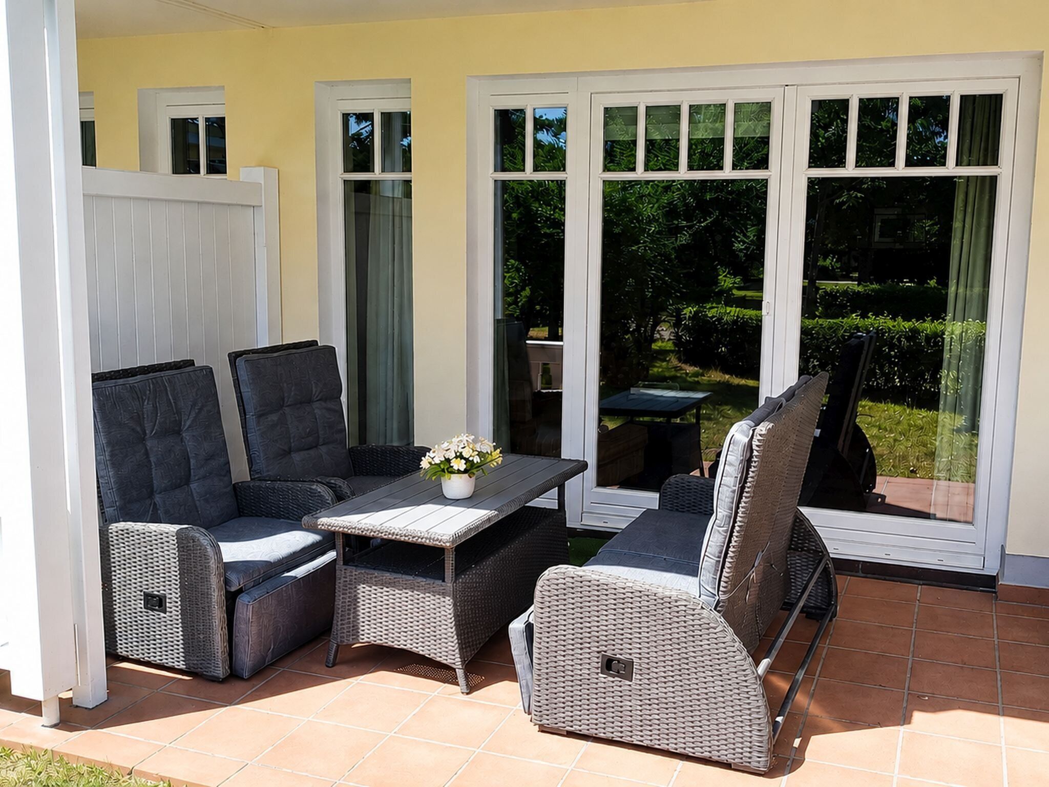 An outdoor patio with a dining table, two sofas, and a chair.