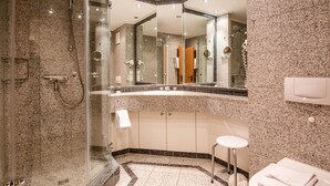 A modern bathroom with a glass-enclosed shower, a toilet, and a sink with a mirror above it.