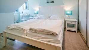 A bedroom with a bed, bedside tables, and a window.