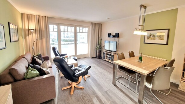 A modern living room with a sofa, chairs, a TV, and a dining table. - Comfortplus vacation apartment with 1 bedroom and terrace on the first floor (Ostseebad Binz)