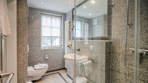 Une salle de bain moderne avec une douche à parois de verre, des toilettes blanches et un lavabo doté d’un porte-serviettes.