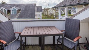 A covered patio with a table and two chairs, overlooking a residential neighborhood. - Komfortplus Ferienwohnung mit 1 Schlafzimmer und Balkon im Dachgeschoss (Ostseebad Binz)