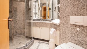 A modern bathroom with a glass-enclosed shower, a vanity with a mirror, and a toilet.