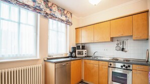 A compact kitchen with wooden cabinets, a built-in dishwasher, a stove, and a microwave.