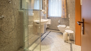 Un baño moderno con ducha envuelta en vidrio, un lavamanos y un inodoro.
