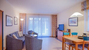 Una sala de estar moderna con un sofá, sillones, una mesa de comedor y un televisor.