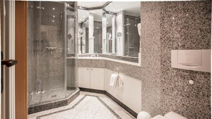 A modern bathroom with a glass-enclosed shower, a vanity with a mirror, and a toilet.
