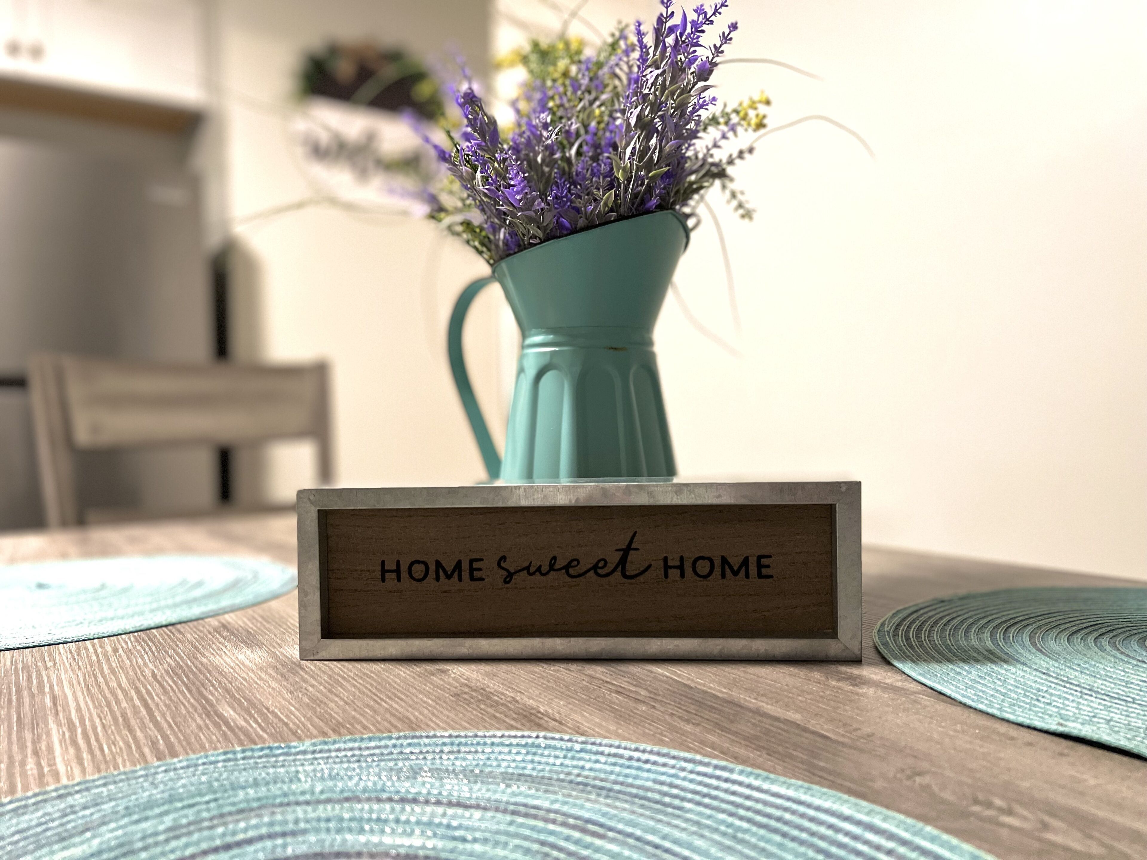 A wooden sign with the text "HOME sweet HOME" in a kitchen setting.