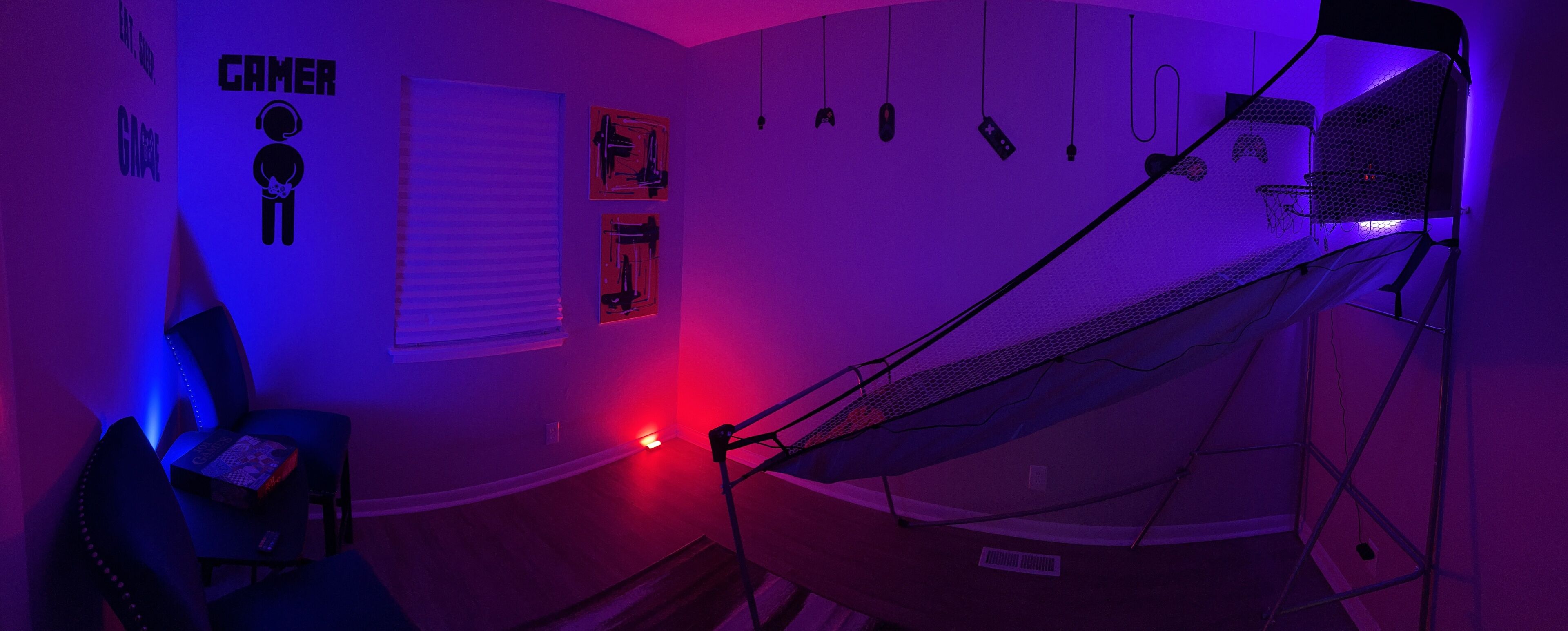 A room with a gaming setup including a chair, a bed with a canopy, and various gaming accessories on the wall.