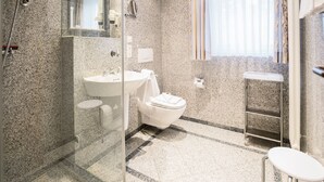 Un bagno moderno con cabina doccia in granito, lavandino bianco e servizi igienici.