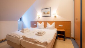Quarto de hotel moderno com uma cama grande, uma mesa de cabeceira, um guarda-roupa de madeira e um quadro na parede.