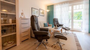 Ein modernes Wohnzimmer mit einer Couch, zwei Sesseln, einem Couchtisch und einer Glasvitrine mit Dekoration.