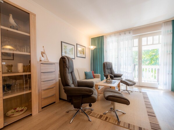 Un salon moderne comprenant un canapé, deux fauteuils, une table basse et un meuble vitré contenant des objets décoratifs.