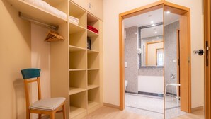 Ein Zimmer mit einem Holzbett, einem Schrank mit Regalen und einem durchgehenden Tür zu einem Badezimmer.