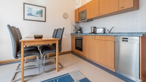 Ett kompakt kök med träskåp, en inbyggd ugn, en kaffebryggare och en diskmaskin från Siemens.