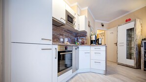 A modern kitchen with white cabinetry, a built-in oven, and a microwave. - Comfortplus vacation apartment with 1 bedroom and terrace on the first floor (Ostseebad Binz)