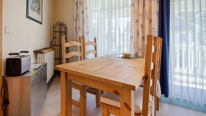 Ein gemütlicher Essbereich mit Holztisch und -stühlen, einem Heizkörper, einem Toaster und einem Fenster mit Vorhängen.