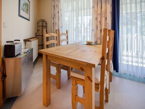 A cozy dining area with a wooden table and chairs, a radiator, a toaster, and a window with curtains.