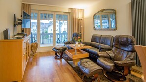 Een ruime woonkamer met een leren bank, een houten salontafel en een tv op een houten kast.