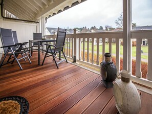 A wooden deck with outdoor furniture, a white railing, and a view of a residential area. - Comfort plus apartment with 2 bedrooms and balcony on the upper floor (Ostseebad Binz)