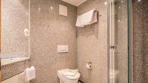 Ein modernes Badezimmer mit Granitwänden, einer Duschkabine aus Glas, einer Toilette und einem Waschbecken.