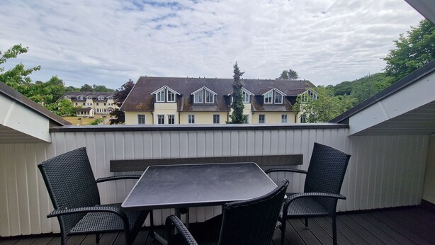 Ein Balkon mit Tisch und Stühlen, mit Blick auf eine Häuserreihe.