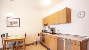A modern kitchen with wooden cabinets, stainless steel appliances, and a dining area with a table and chairs.