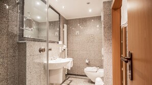 A modern bathroom with a glass shower enclosure, a white sink, and a toilet.