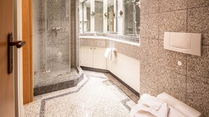 A modern bathroom with a glass-enclosed shower, granite countertops, and a large mirror.