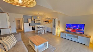 Ein modernes Wohnzimmer mit Sofa, Couchtisch, Fernseher und Küchenzeile.