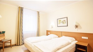 A hotel room with a double bed, a desk, a chair, a nightstand, and a picture on the wall. - Comfort apartment with 1 bedroom and balcony on the upper floor (Ostseebad Binz)