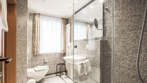 A modern bathroom with a glass shower enclosure, a sink, and a toilet. - Comfort apartment with 1 bedroom and balcony on the upper floor (Ostseebad Binz)