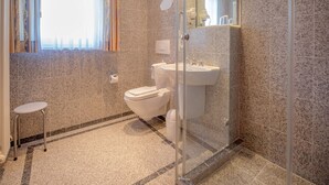 A modern bathroom with a glass shower enclosure, a toilet, and a sink. - Comfort apartment with 1 bedroom and balcony on the top floor (Ostseebad Binz)