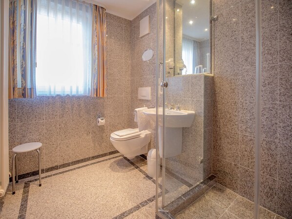 A modern bathroom with a glass shower enclosure, a toilet, and a sink.