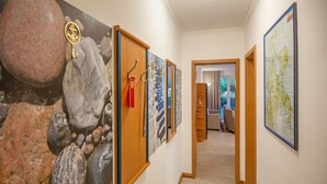 Un couloir avec un mur en pierre, des portes en bois et des œuvres d’art encadrées.