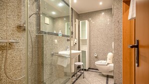 Une salle de bain moderne avec une douche à parois de verre, un lavabo et des toilettes.