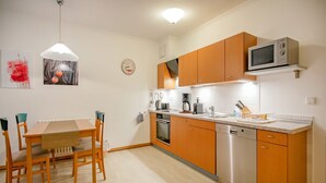 Une cuisine moderne avec des meubles en bois, des appareils électroménagers en acier inoxydable et un coin repas comprenant une table et des chaises.