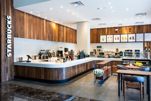 A modern Starbucks with a wooden interior, a counter with coffee machines, and seating areas.