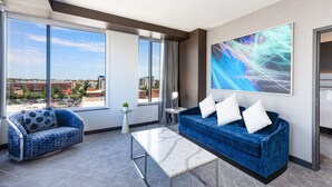 A modern hotel room with a large window, a blue sofa, a white coffee table, and a city view. - Renaissance Oklahoma City Downtown Bricktown Hotel (Oklahoma City)