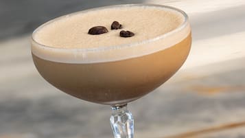 A cocktail in a stemmed glass on a marble surface.