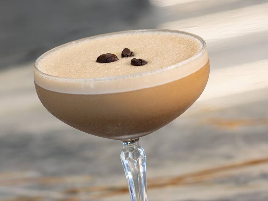 A cocktail in a stemmed glass on a marble surface.